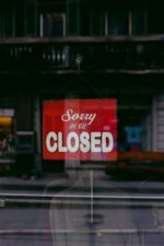 Red 'Sorry We Are Closed' sign displayed in a shop window indicating closure.